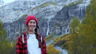 活跃的年轻时髦女孩穿过树林，沿着山间的小路走。 她戴着一顶红帽子
