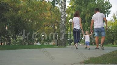 爸爸和<strong>妈妈</strong>和儿子<strong>牵</strong>着<strong>手</strong>在公园里。 家人在公园散步。