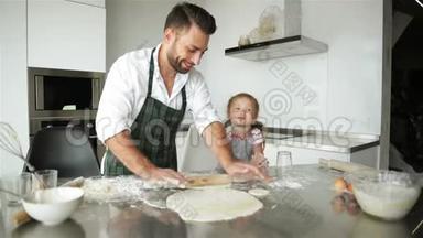 幸福的家庭一起做饭。 年轻的父亲正在帮她女儿做饭。
