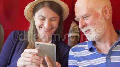 父亲和他的女儿在高速国际列车上使用智能手机。 退休后积极的现代生活。 快乐