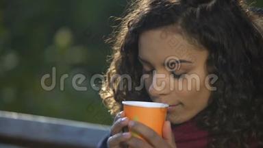 年轻的卷发女士在户外享受最喜欢的早间咖啡