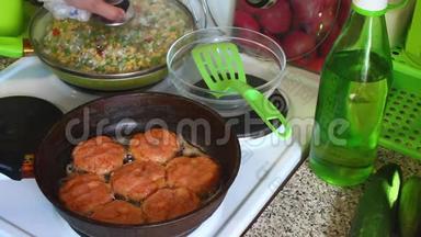女人把蔬菜混合物盖在煎锅里。 旁边的煎锅炒肉丸从鲑鱼。