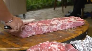 用白手套烹饪，从一大块生肉中切下牛排。 优质猪肉粉嫩