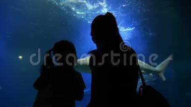 母亲带着可爱的孩子在母亲节参观海洋馆。 妈妈给女孩看了这个美丽有趣的世界