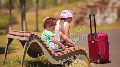 男孩和女孩坐在长凳上，提着一个手提箱