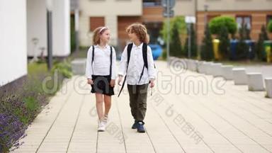 男孩和女孩从学校回来说话。 孩子们穿着校服，背着背包