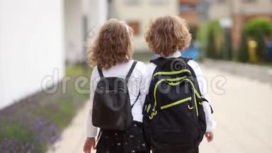 两个卷曲的学童，一个男孩和一个女孩，带着背包上学。 后景。 回到学校，知识日
