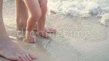 特写，在潮湿的沙子上，有男孩子`脚.. 一个波浪进来了。 海滨度假，暑假