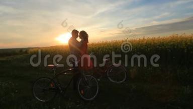 在盛开的田野里，带着自行车的敏感相爱的夫妇。 新郎正在温柔地抚摸他爱人的脸