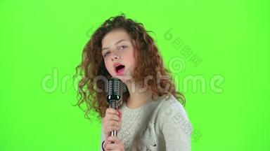 少女用复古麦克风唱火辣辣的歌。 绿色屏幕