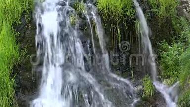 瀑布从岩石中溅出，绿草如茵，美丽的春天瀑布