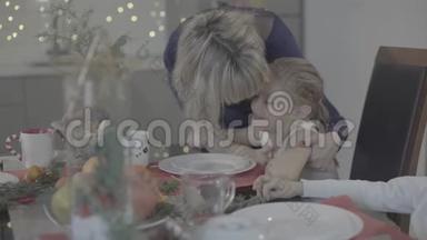 爱的母<strong>亲亲</strong>吻可爱的小女儿，坐在餐桌上，在舒适可爱的<strong>节</strong>日气氛中庆祝圣诞<strong>节</strong>