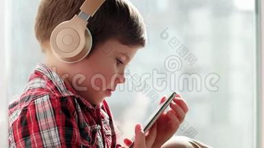 戴着耳机的孩子微笑着，小男孩在电子设备上看动画片，为孩子准备的设备