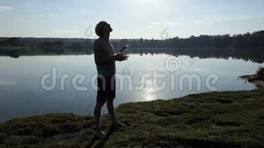 年轻人抬起头，在斯洛莫的湖岸上操作一架无人机