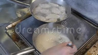 一位专业厨师在餐厅的厨房里用不锈钢盘子准备食物。饺子的制作