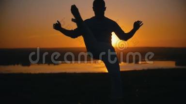 一个人在夕阳下慢动作的背景下表演战斗技巧