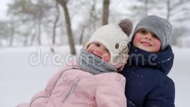 幸福的家庭在下雪的冬天滑雪。 父亲和母亲在下雪时带着儿子和女儿拉雪橇。 男孩和女孩