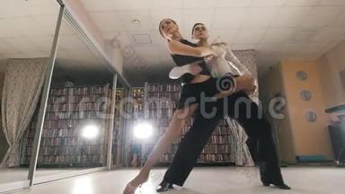 年轻迷人的男人和女人在工作室里穿着服装跳舞拉丁美洲舞蹈，专注于脚，从视野中看到。