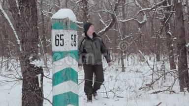 在冬天的森林里，一个人走在一个四分之一的柱子旁边。 林业检查。