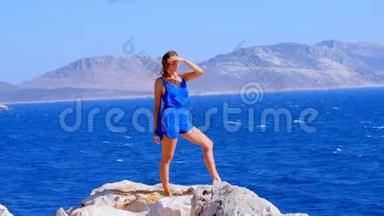 美丽的女人穿着蓝色的整体服装靠近大海