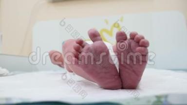 刚出生的小男孩躺在背上。 宝宝在踢和伸展腿，读手指。 小底的特写镜头