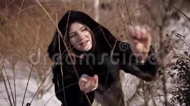 穿着皮毛大衣的女孩冬天从灌木丛中摘下黑色浆果