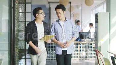 两位年轻的亚洲企业家在办公室讨论生意
