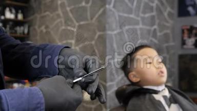 戴着黑色手套的理发师正准备剃一个亚洲小孩60<strong>英尺</strong>高的直剃须刀