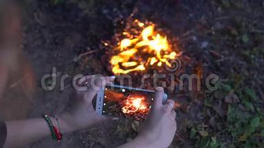 这位女士用智能手机<strong>露营视频</strong>拍摄了明亮的篝火。