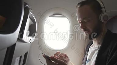 飞机上的人戴着耳机点击智能手机的屏幕。