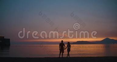 夕阳下的爱情故事。 在岸边站着的时候，男人和女人彼此温柔地接吻