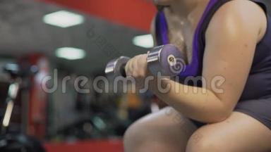 胖女孩在健身房用哑铃锻炼，努力减肥