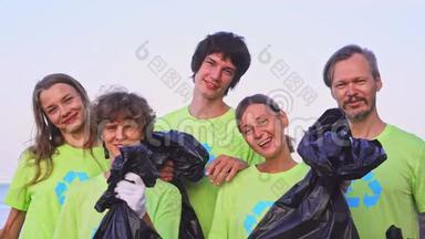 5名年轻志愿者身穿绿色t<strong>恤衫</strong>，将图像回收，在海洋海滩上收集垃圾，然后在相机上摆姿势