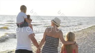 两个小妹妹和快乐的母亲和父亲在海滩上<strong>牵手散步</strong>的后景