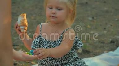 小女孩吃羊角面包，试着从女`手里拿出一颗五颜六色的糖果
