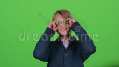 十几岁的孩子在绿色的屏幕上带着两只比特币微笑
