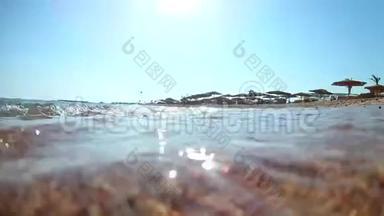 阳光明媚的一天，海浪拍打着沙滩上的海浪，带着草的沙滩伞，红海，从下面可以看到广阔的视角