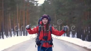快乐的游客开始了她的旅行，在阳光明媚的冬季森林里沿着道路奔跑。 高清。