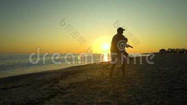 日落时，一个年轻英俊的男人和他的小女儿沿着海滨散步。 爸爸把女儿抱在<strong>怀里</strong>