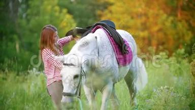 在夏天的田野里，年轻女子把马鞍固定在马上