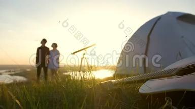 在日落时分在户外享受暑假的年轻夫妇面前草地上的吉他