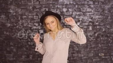 一个戴着黑帽子<strong>的</strong>女孩正在一面<strong>有质感的</strong>墙上跳舞
