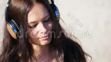 夏天，在大海的背景下。 美丽的女人，留着长长的黑发，听着耳机里的音乐