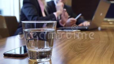 特写一杯水和一个躺在桌子上的iPhone
