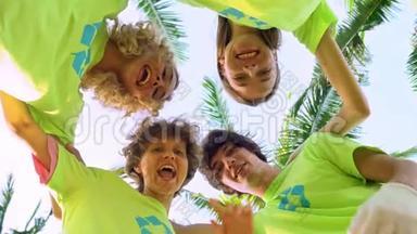 四名年轻志愿者身穿绿色t<strong>恤衫</strong>，照片上的是一个海滩上棕榈树下的一个小丘