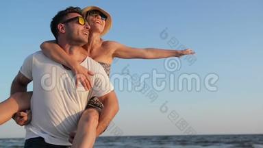 喜笑颜开幸福的夫妻在海边享受阳光般的天气。 强壮的男人把<strong>女友</strong>抱在蓝肩上