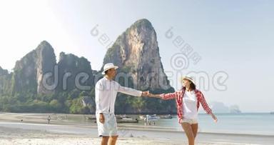 情侣在沙滩上散步牵手谈情说爱的年轻人和女人在度假拥抱游客
