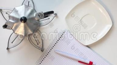 一个男人从桌子上的杯子里喝咖啡。 然后他拿起一支笔，思考在笔记本上写什么。 在我的桌子旁边