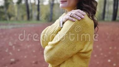 一个穿着黄色毛衣的年轻女子在秋天公园散步。 黑发女人在寒冷的森林里晒太阳。 恋爱中的女人