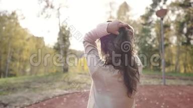一个穿毛衣的年轻女子在秋天公园散步。 黑发女人在寒冷的森林里晒太阳。 公园里的浪漫女人